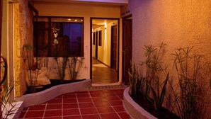 A hotel entrance with a tiled pathway, a stone wall, and potted plants. - Spacious 9-bedroom house in wonderful La Calera with WiFi (La Calera)