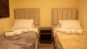 Two twin beds with headboards, a wooden nightstand between them, and a small shelf. - Spacious 9-bedroom house in wonderful La Calera with WiFi (La Calera)