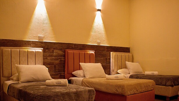 A hotel room with three beds, each with a headboard and pillows, and a wooden accent wall. - Spacious 9-bedroom house in wonderful La Calera with WiFi (La Calera)