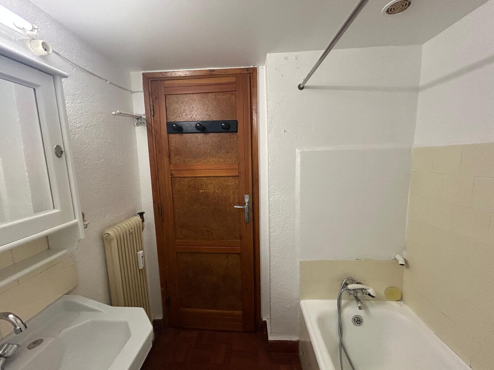 Ein Badezimmer mit Holztür, einer Badewanne und einem Waschbecken.