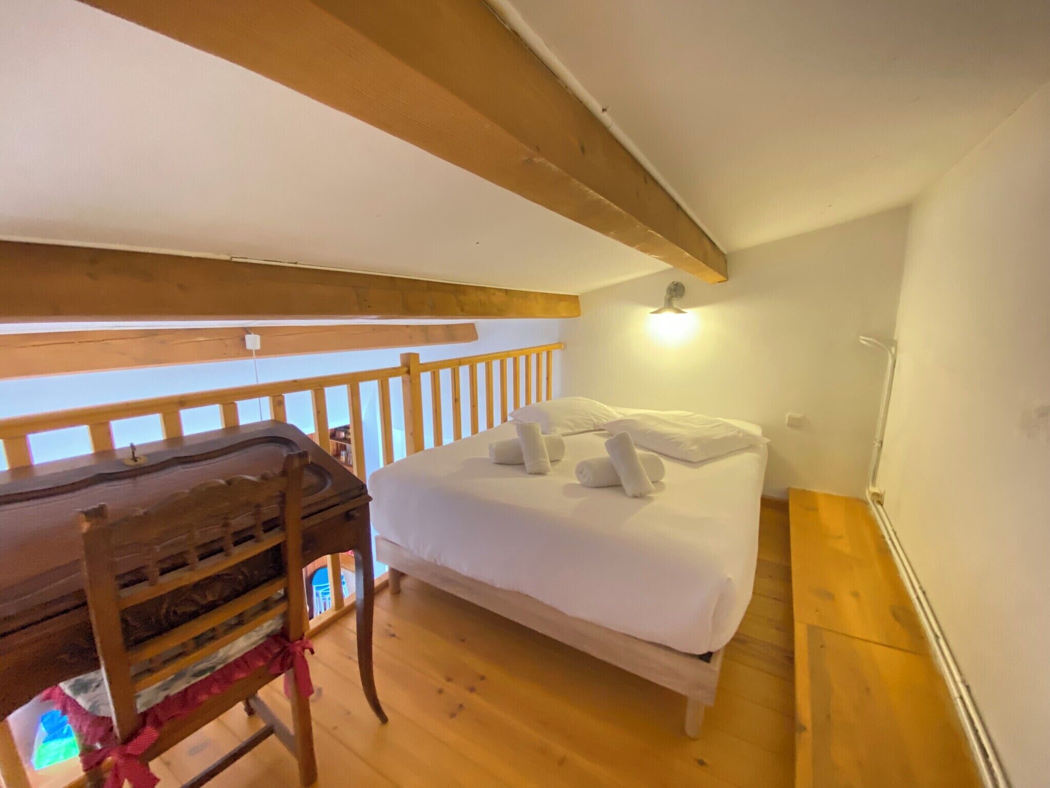Um quarto com uma cama de madeira, uma escrivaninha e uma cadeira.