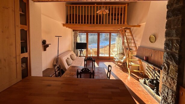Une pièce chaleureuse avec un plafond en bois, un canapé, une télévision et une cheminée en pierre.