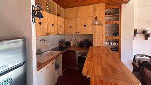 Une cuisine compacte avec des meubles en bois, un lave-vaisselle encastré, un évier et un plan de travail en bois.