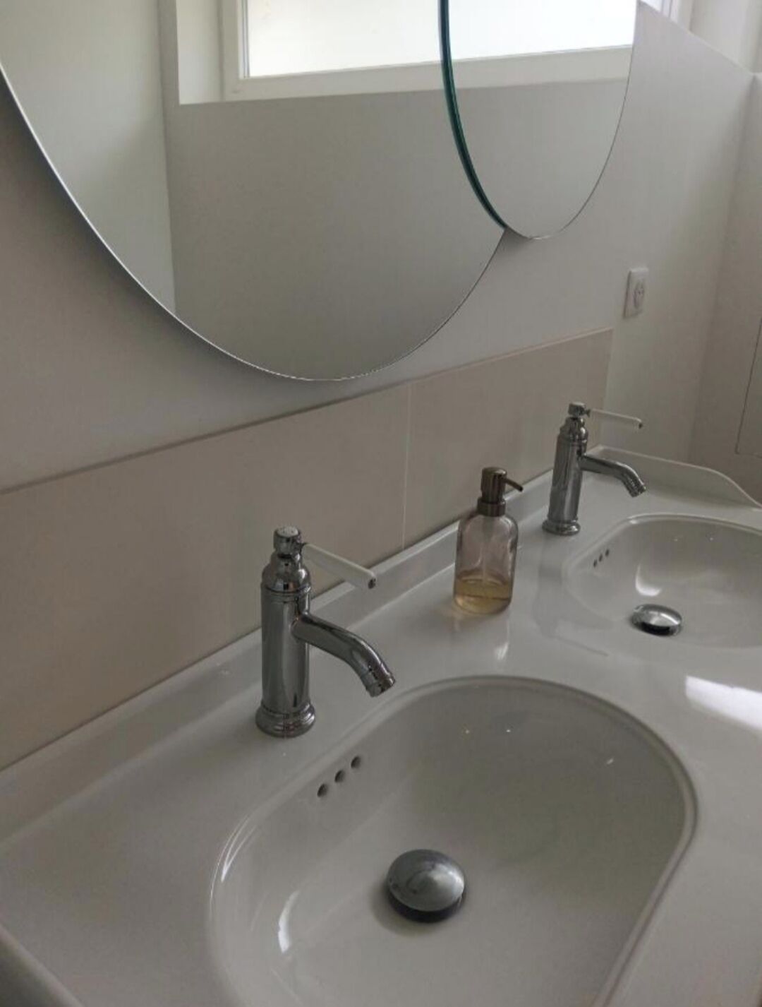 Ein Badezimmer mit zwei Waschbecken, einem Spiegel und einem Fenster.
