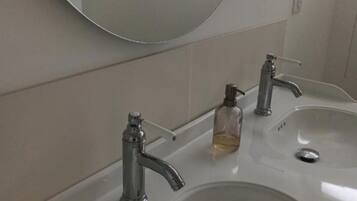 Een badkamer met twee wastafels, een spiegel en een raam.