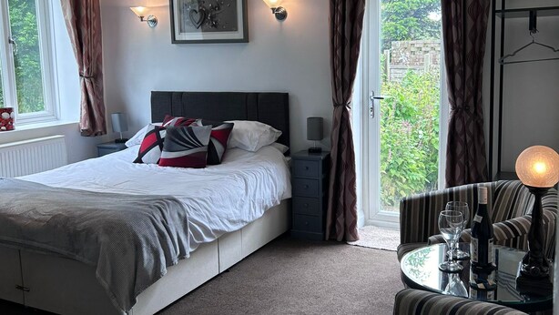Une chambre à coucher avec un lit, des tables de chevet, une chaise, une lampe et une fenêtre avec des rideaux.