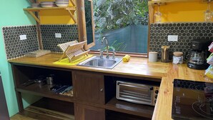 Een keuken met een houten aanrecht, een spoelbak, een broodrooster en een raam met uitzicht op groen.