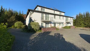 Un bâtiment à deux étages avec une allée pavée et un petit jardin.