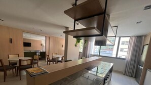 Una cocina moderna con encimera de mármol, horno empotrado y comedor con sillas y mesa de madera.