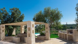 An outdoor patio area with stone structures, a pool, and a view of the surrounding greenery. - Trulli Dei Ciclamini - Locorotondo (Locorotondo)