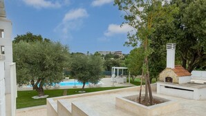 A pool area with a gazebo, outdoor seating, and a stone oven.