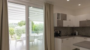 A modern kitchen with white cabinets, a coffee machine, and a dining area with a table and chairs.