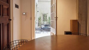 Pasillo que conduce a un balcón con mobiliario exterior y vistas a la vegetación.