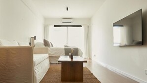 Una sala de estar moderna con un sofá, una mesa de centro y un televisor de pantalla plana montado en la pared.