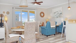 A dining area with wicker chairs and a table, a blue armchair, and a ceiling fan. - Summerhouse 309 (Port St. Joe)