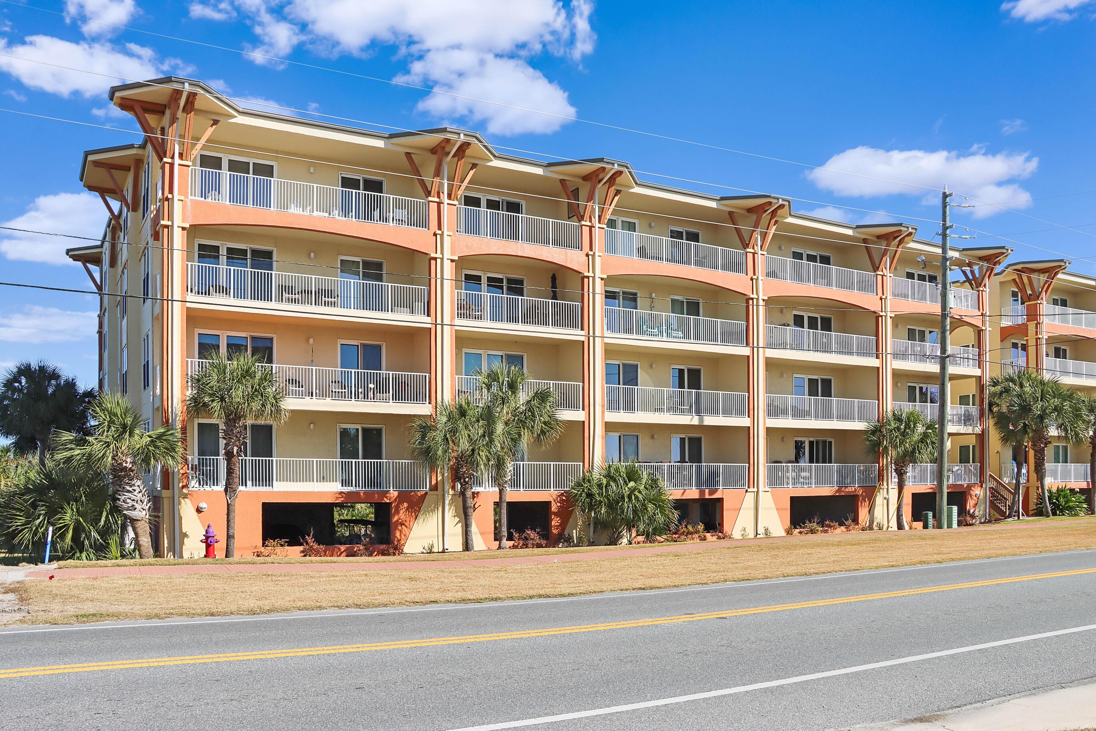 A multi-story hotel with balconies, palm trees, and a clear sky.