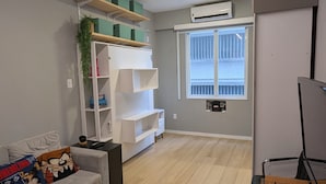 Ein geräumiges Wohnzimmer mit grauem Sofa, Holzboden und Einbauschränken.