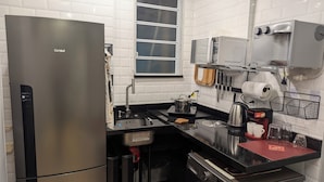 Eine moderne Küche mit einem Edelstahl-K ühlschrank, einer Mikrowelle, einem Wasserkocher und einer Kaffeemaschine.
