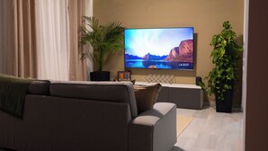 A modern living room with a flat-screen TV, a sofa, and two potted plants. - Comfy Stylish Stay in Malaga (Malaga)