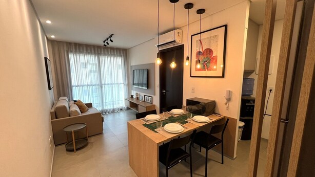 Een modern appartement met een eethoek, een bank, een televisie en een keuken.