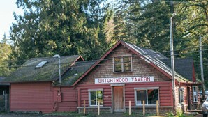 A red building labeled "Brightwood Tavern" with a sloped roof, surrounded by tall trees. - Relaxing River Lodge • Hot Tub • Family Friendly (Rhododendron)