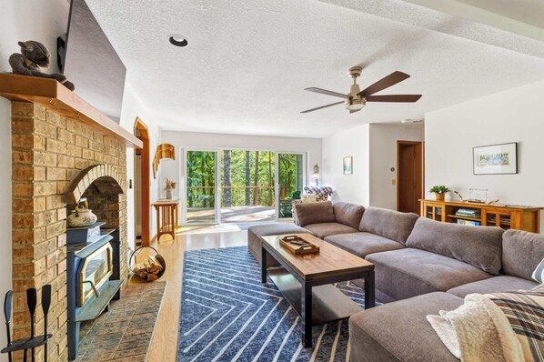 A spacious living room with a fireplace, a sofa, a coffee table, and a ceiling fan. - Relaxing River Lodge • Hot Tub • Family Friendly (Rhododendron)