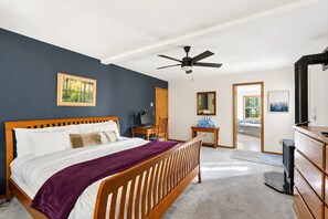 A bedroom with a bed, a desk, a chair, a ceiling fan, and a view of the outside. - Winter Lodge • Hot Tub • Wood Stove • Sleeps 10 (Rhododendron)