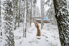 A snow-covered forest with a wooden staircase leading to a house. - Winter Lodge • Hot Tub • Wood Stove • Sleeps 10 (Rhododendron)