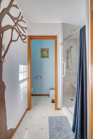 A narrow hallway leading to a bathroom with a shower, a toilet, and a sink. - Relaxing River Lodge • Hot Tub • Family Friendly (Rhododendron)