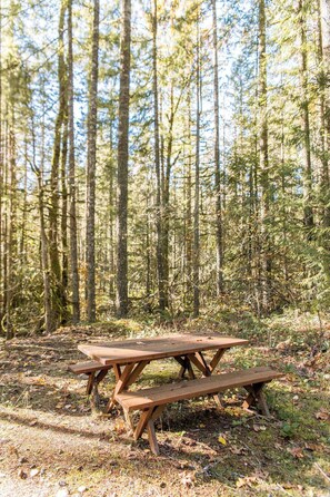 A wooden picnic table in a forested area. - Relaxing River Lodge • Hot Tub • Family Friendly (Rhododendron)