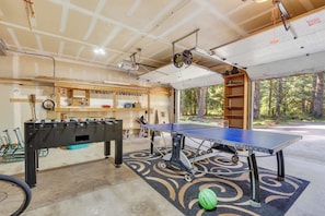 A garage with a foosball table, ping pong table, and a bicycle. - Relaxing River Lodge • Hot Tub • Family Friendly (Rhododendron)