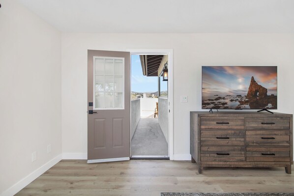 Un couloir avec un plancher en bois, une porte donnant sur l’extérieur et une commode en bois avec des tiroirs.