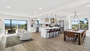 A modern kitchen with a large island, white cabinetry, and pendant lighting.