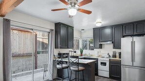 Una cucina moderna con mobili scuri, un frigorifero in acciaio inossidabile, un fornello e una ventola a soffitto.