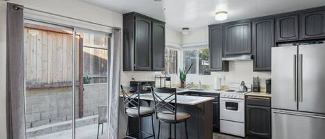 Una cocina moderna con armarios oscuros, un refrigerador de acero inoxidable, una estufa y un ventilador de techo.