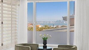 Ein Zimmer mit großem Fenster, einem Tisch mit Blumenvase und zwei Stühlen.