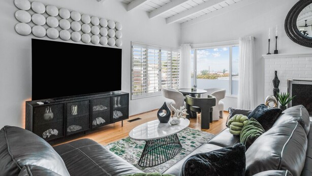 Ein modernes Wohnzimmer mit großem Flachbildfernseher, Kamin und Balkon mit Aussicht.