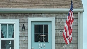 A house with a light blue door, a number '46' on the wall, an American flag, and two potted plants on the front steps. - Amazing Water Front 4-bedroom estate in charming Narragansett with AC, WiFi (Narragansett)