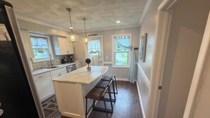 A kitchen with a central island, wooden flooring, and pendant lighting. - Amazing Water Front 4-bedroom estate in charming Narragansett with AC, WiFi (Narragansett)