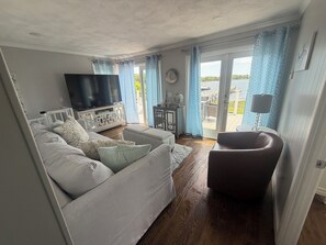 Una sala de estar con un sofá, un televisor y vistas al exterior.
