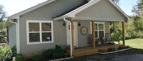 A single-story house with a covered porch, a front door, and a small garden area.