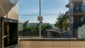 Una habitación con un ventanal grande, chimenea de mármol y vistas a una zona residencial con casas y palmeras.