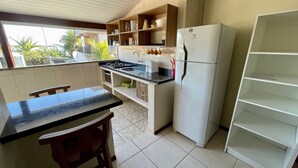 Una cocina con encimera de mármol, estufa, pileta y refrigerador.