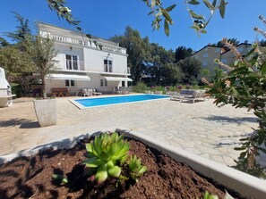 Guests can enjoy a balcony with a view, a refreshing pool surrounded by lush greenery, and comfortable lounge seating.