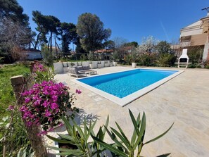 Relax by the pool surrounded by lush greenery and comfortable seating.