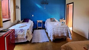 A room with two beds, a red dresser, a small table, and a blue accent wall.