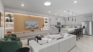 Une cuisine moderne avec des meubles blancs, un îlot central et des luminaires suspendus.