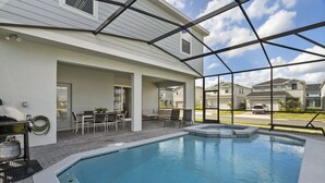 Ein Schwimmbecken mit Whirlpool, Terrassenmöbeln und Grillplatz.