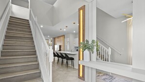 Ein modernes Interieur mit einer Treppe, einer Küchenzeile und einer Bar mit Hockern.