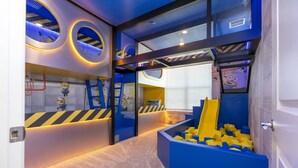 Un espace de jeux pour enfants avec un toboggan, des structures d’escalade et une piscine à balles.